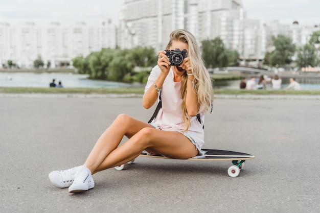 カメラに写っているスケートボード付きの長い髪の少女。ストリート、アクティブスポーツ