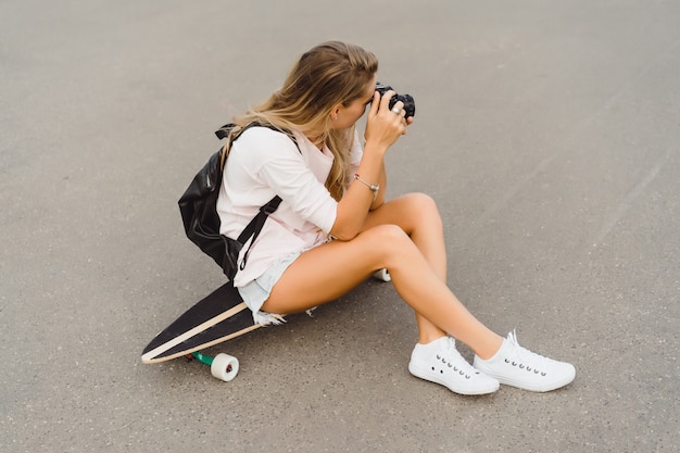 카메라에 촬영하는 스케이트 보드와 긴 머리를 가진 여자. 거리, 활동적인 스포츠