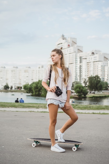 girl with long hair with skateboard photographing on camera. street, active sports