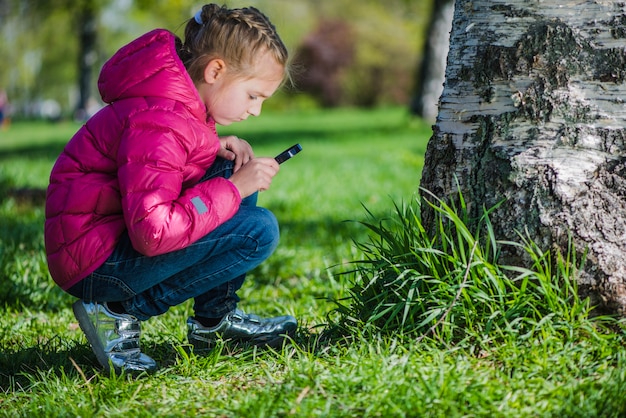 Girl with magnifying glass looking at the lawn