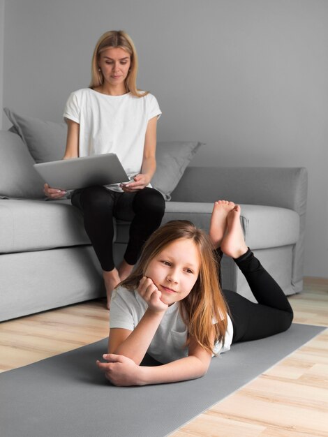Девушка с мамой занимаются спортом на коврике