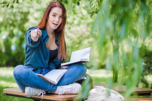 Girl with notebooks pointing at camera