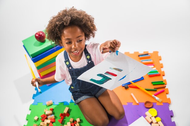 Girl with painted paper on play mat in studio