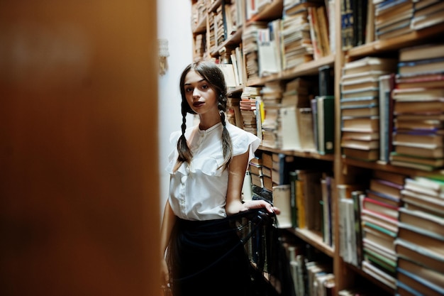 Foto gratuita ragazza con le trecce in camicetta bianca alla vecchia biblioteca