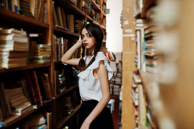 Girl with pigtails in white blouse at old library