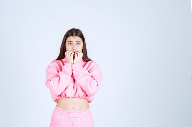 Girl with pink pijamas looks scared and terrified