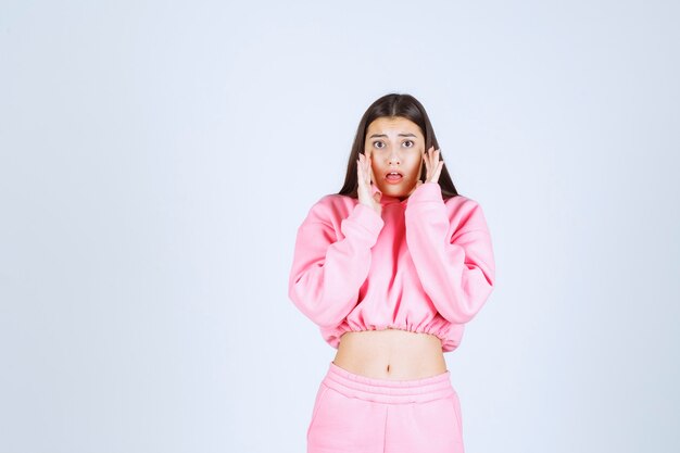 Girl with pink pijamas looks scared and terrified