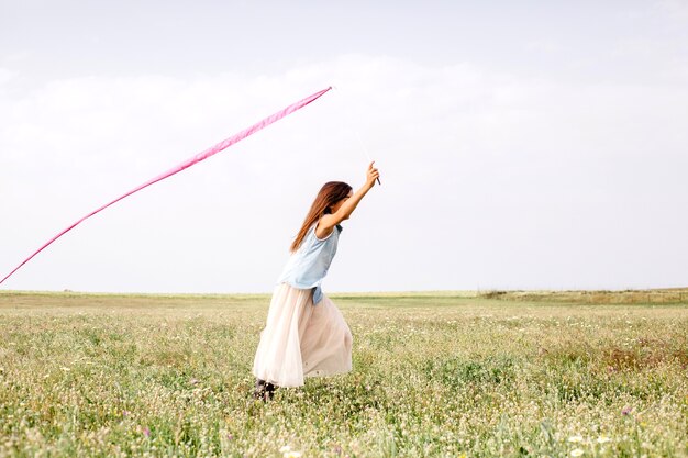 Free Photo girl with pink ribbon running in field