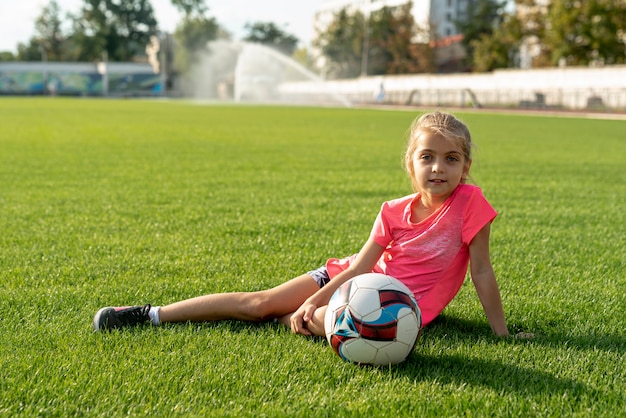 Girl with pink shirt sitting on grass