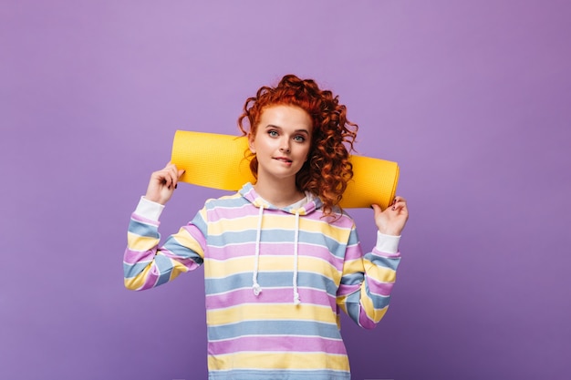 Girl with ponytail holds yoga mat