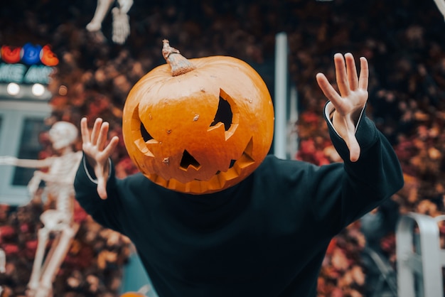 Girl with a pumpkin head scares at the camera