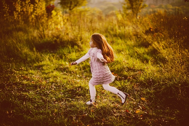 Girl with red hair walks on the fallen leaves