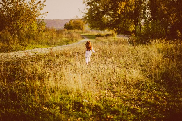赤い髪の女の子が緑の草の上を歩く