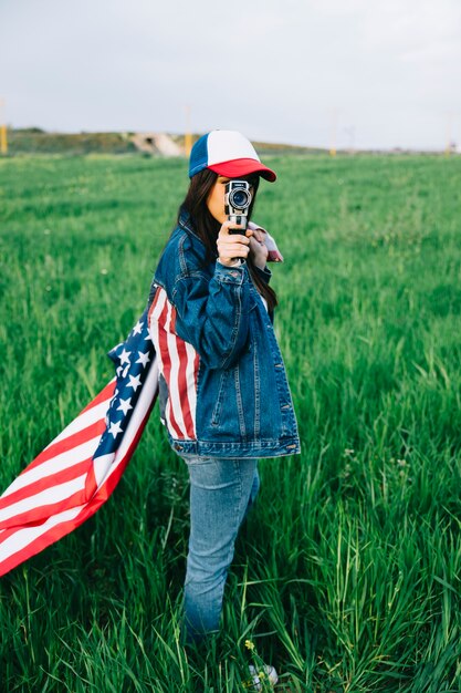 Girl with retro camera staying in field 