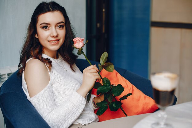 Una ragazza con la rosa e dessert nella caffetteria