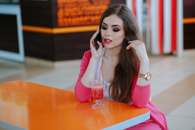 Foto gratuita ragazza con viso serio parlando al telefono, seduta in un ristorante