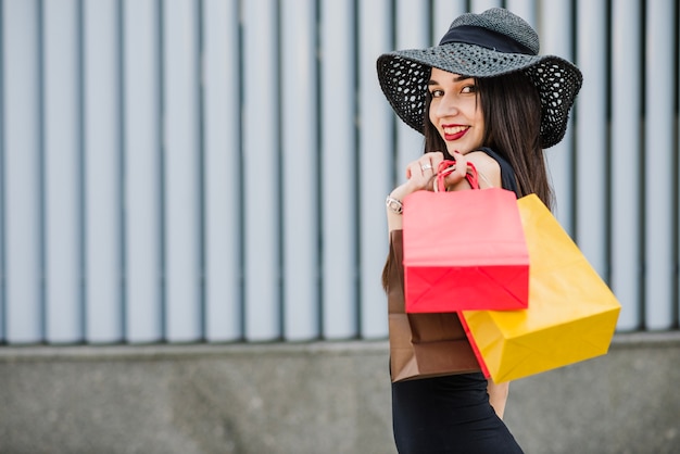 Ragazza con borse della spesa che presentano fuori