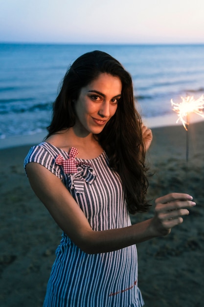 Free photo girl with sparkler at the beach