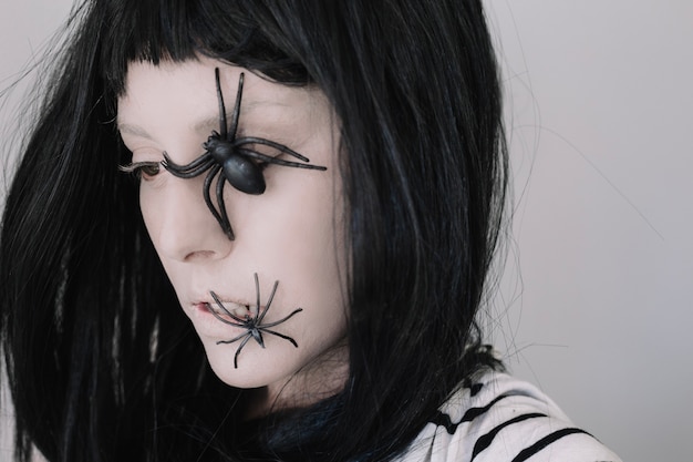 Foto gratuita ragazza con ragni sul volto che guarda lontano