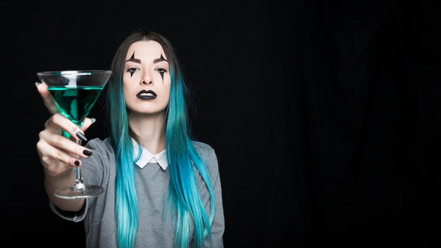 Girl with spooky makeup holding glass goblet