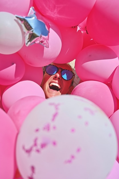 Free photo girl with sunglasses laughs among pink balloons