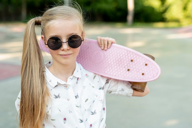 Girl with sunglasses and pink skateboard