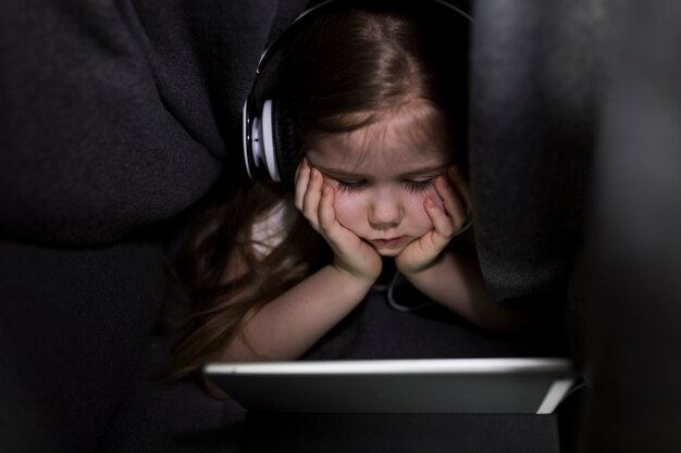 Girl with tablet under blanket