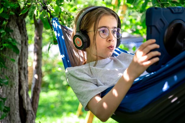 Girl with a tablet in a hammock in the garden