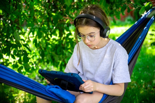 Free photo girl with a tablet in a hammock in the garden
