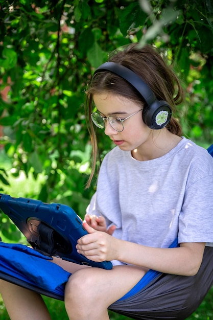 Girl with a tablet in a hammock in the garden