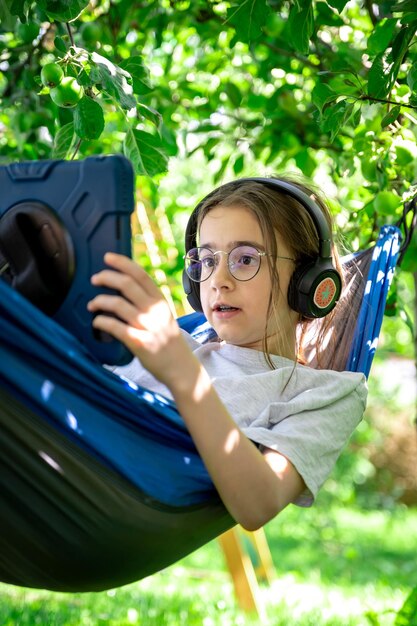 Girl with a tablet in a hammock in the garden