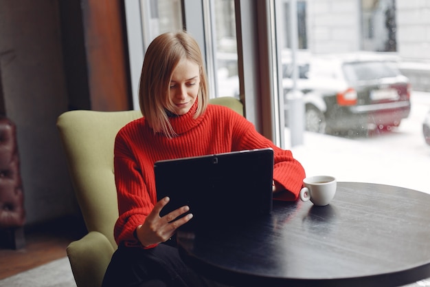 Girl with a tablet. Woman in a cafe. Lady sitting at the table.