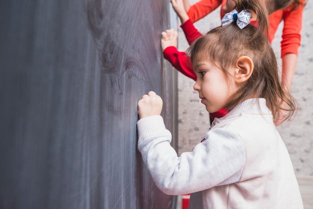 Foto gratuita ragazza con le code scrivendo sulla lavagna