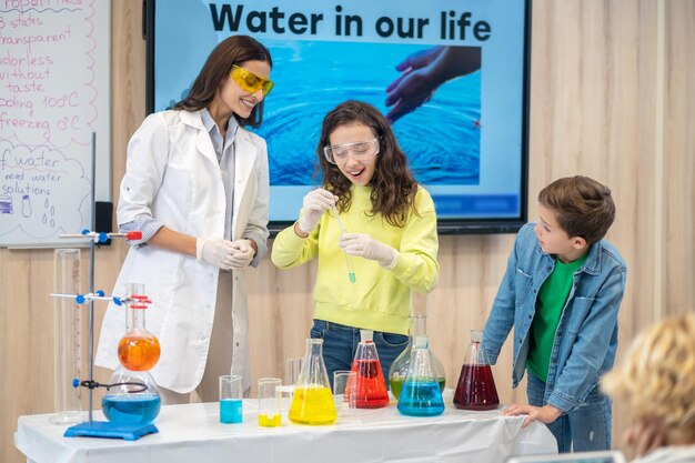 Girl with test tube and watching teacher with children