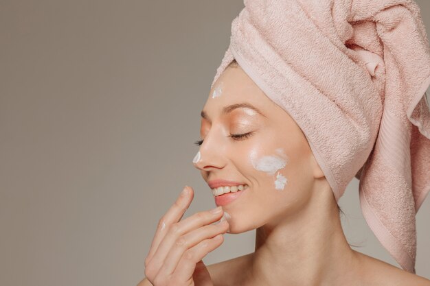 Girl with towel on the head using lotion