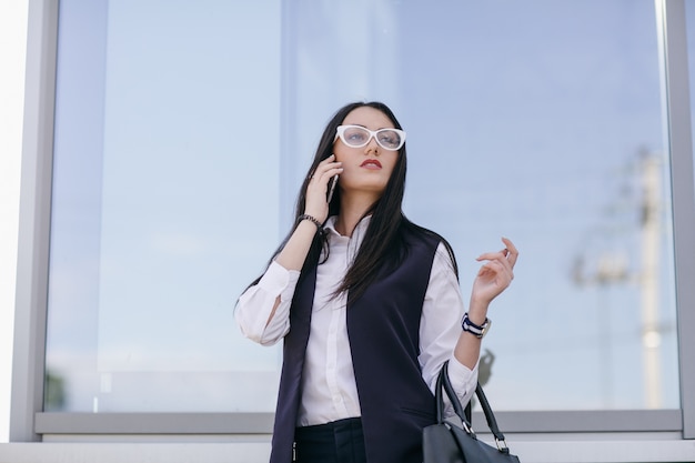 携帯で話している透明のガラスを持つ少女