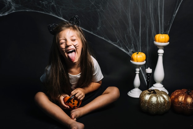 Foto gratuita ragazza con cesto o dolcetto vicino decorazioni di halloween