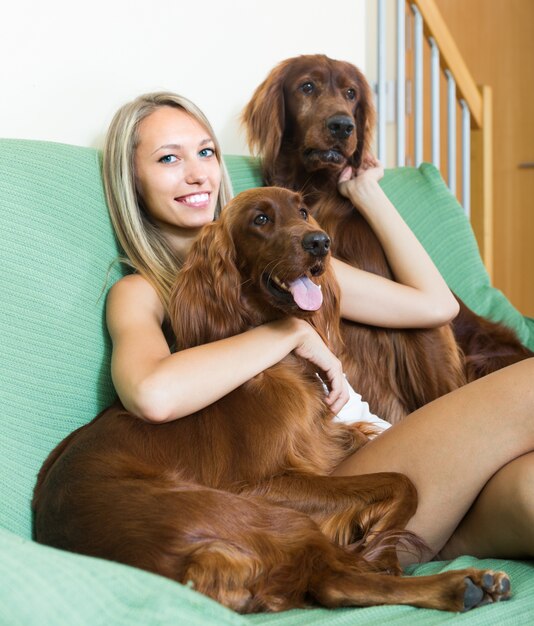 Girl with two Irish setters at home