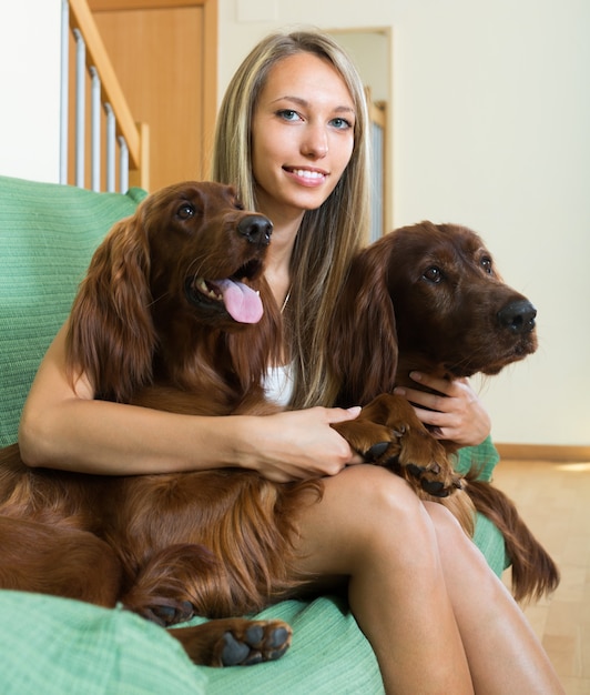 Girl with two Irish setters at home