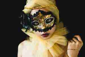 Foto gratuita ragazza con un ornamento di colore giallo sulla testa e una maschera veneziana