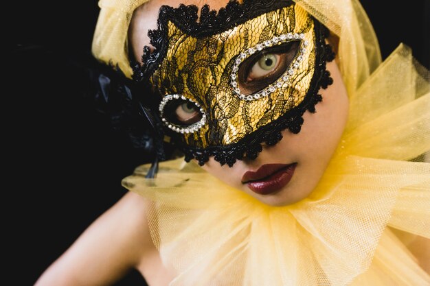 그녀의 머리와 베네치아 마스크에 노란색 장식으로 소녀