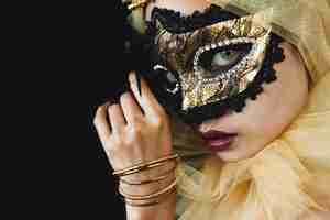 Free photo girl with a yellow ornament on her head and a venetian mask