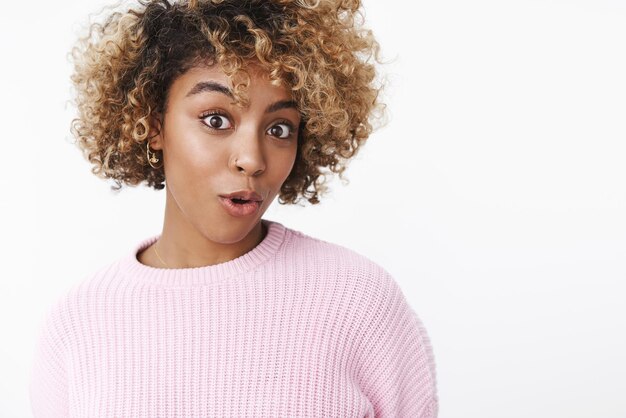 Girl wondering as feeling surprised hearing interesting rumor folding lips raising eyebrow curiously and gazing amazed and impressed at camera standing intrigued over white background