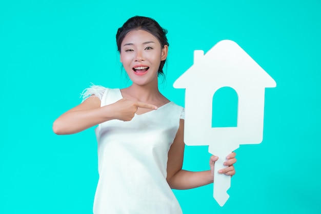 The girl wore a white long-sleeved shirt with floral pattern, holding the house symbol and showing various gestures with a blue .