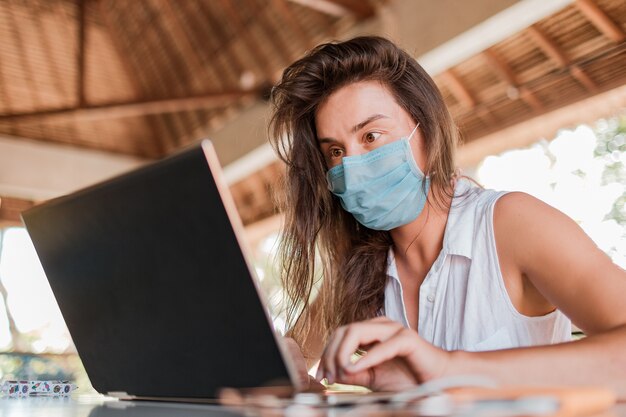 Girl working on laptop in a mask.  High quality photo