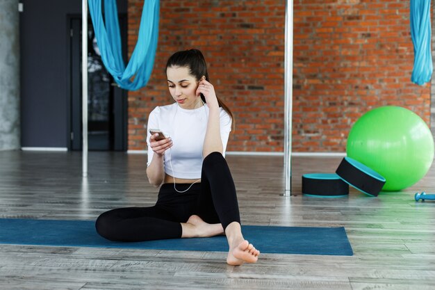 Girl works with her smartphone after or before a work out in the gym