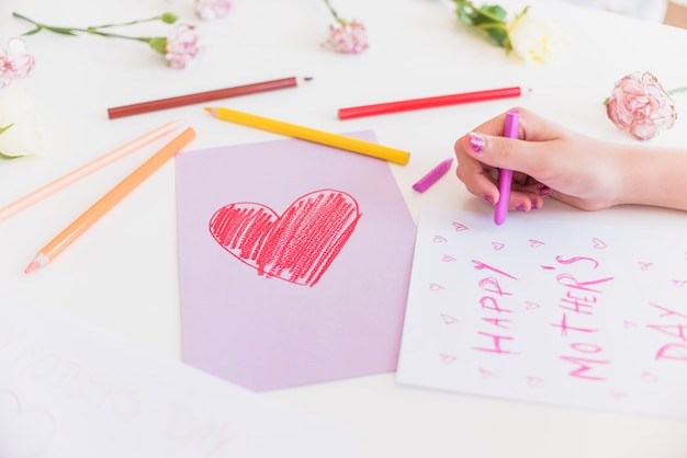 Girl writing happy mothers day on paper sheet