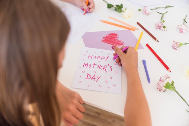 Girl writing Happy Mothers Day on paper 
