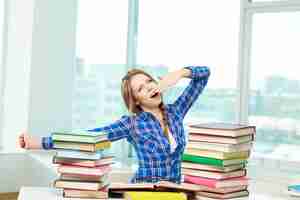 Free photo girl yawning surrounded by books