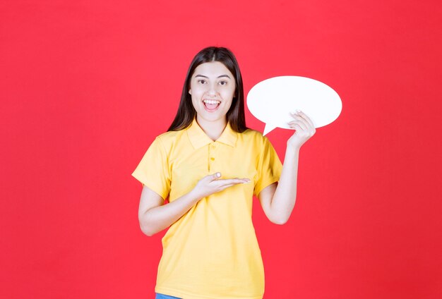 Girl in yellow dresscode holding an ovale info board.